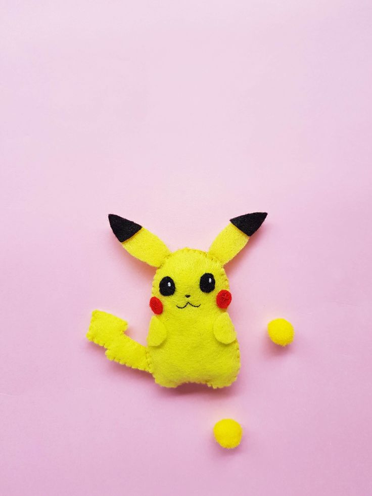 a pikachu pinata laying on top of a pink surface next to some yellow balls