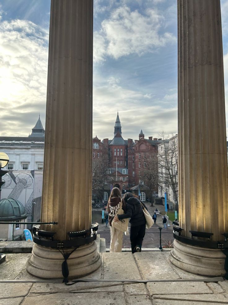 two people and a dog standing in front of some large pillars