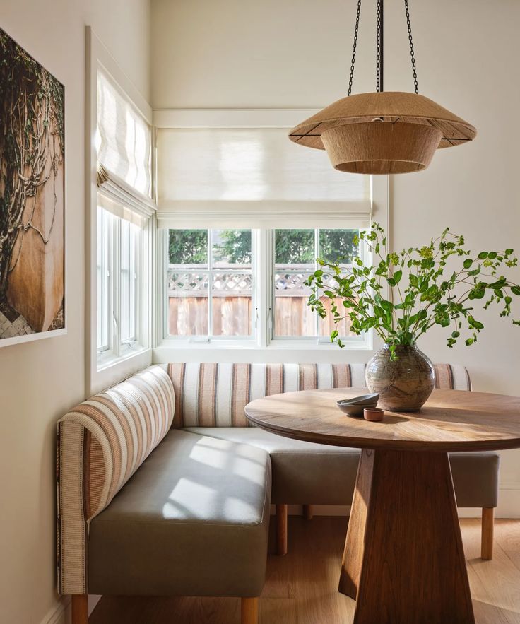 a wooden table sitting under a window next to a bench