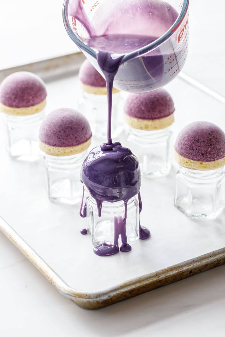 purple desserts are being poured onto a tray