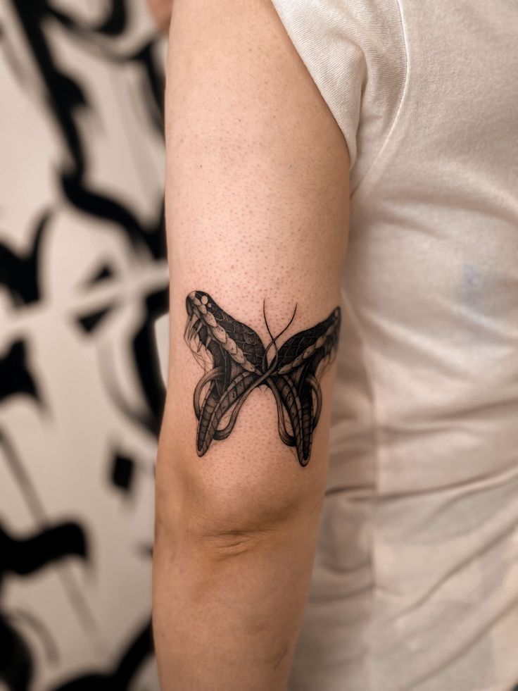 a woman with a butterfly tattoo on her arm, showing it's black outline