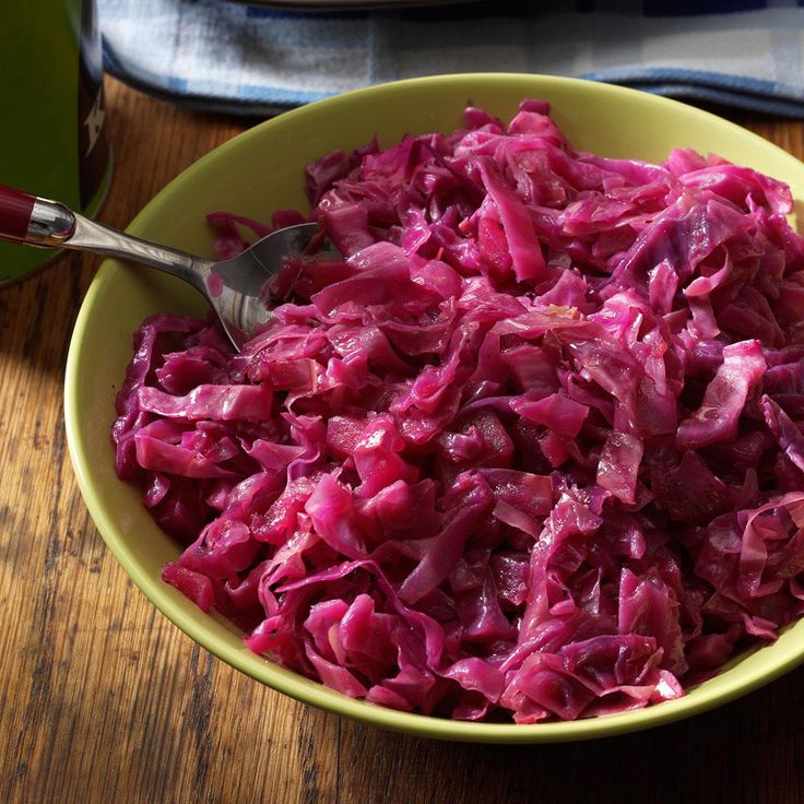 a bowl filled with red cabbage on top of a wooden table