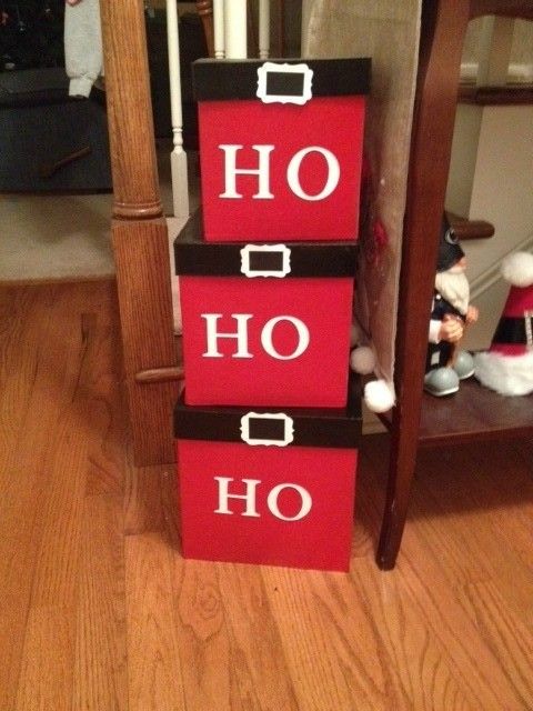 a stack of red boxes sitting on top of a wooden floor next to a christmas tree