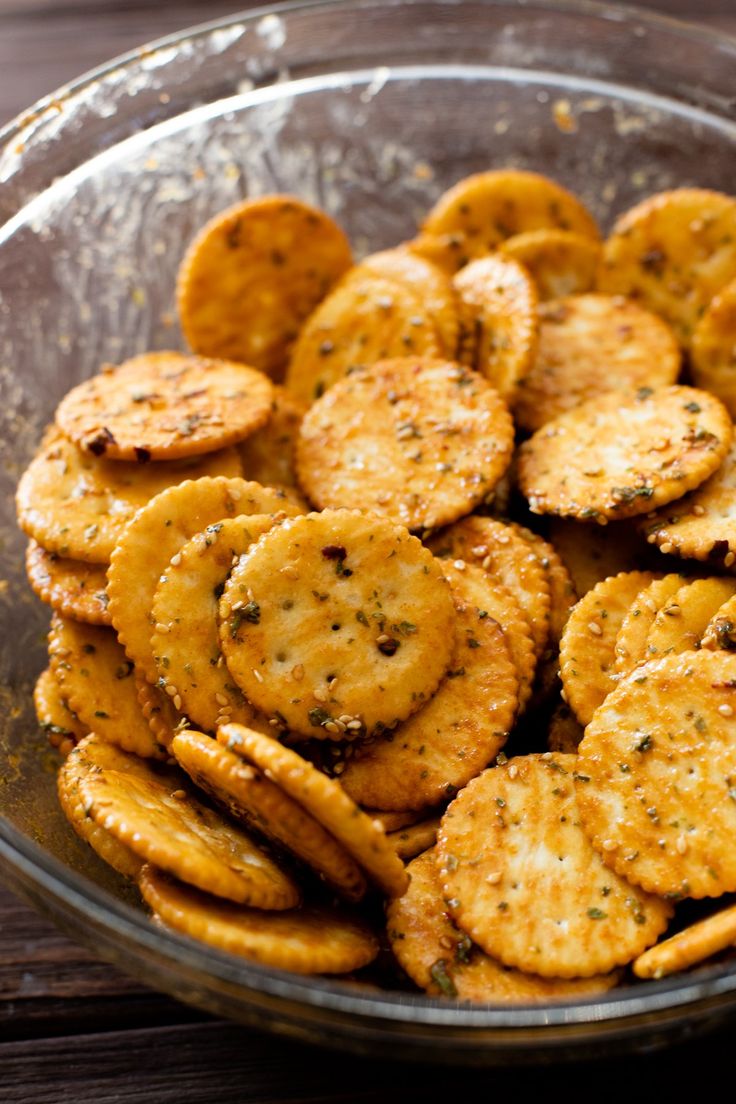 a glass bowl filled with crackers on top of a wooden table