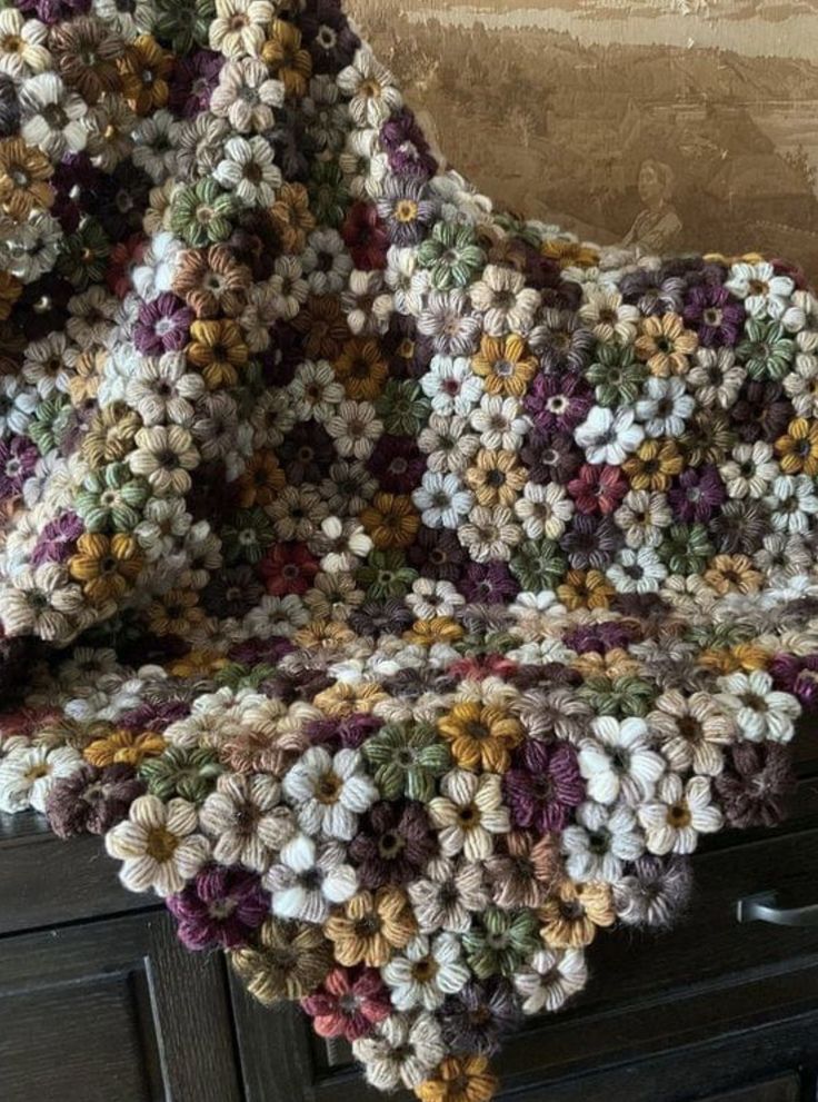 a crocheted blanket sitting on top of a dresser next to a wooden drawer