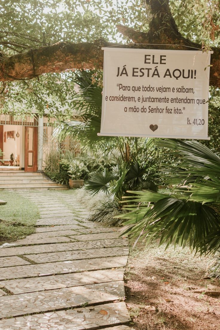 a sign hanging from the side of a tree in front of a building with lots of trees