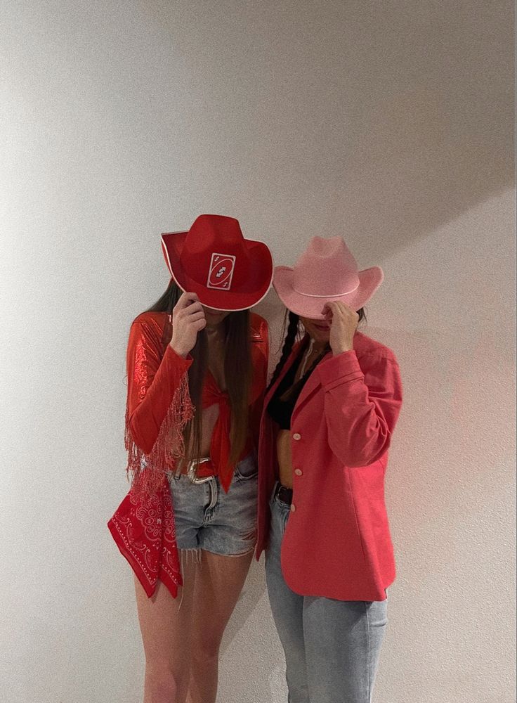 two women standing next to each other wearing hats