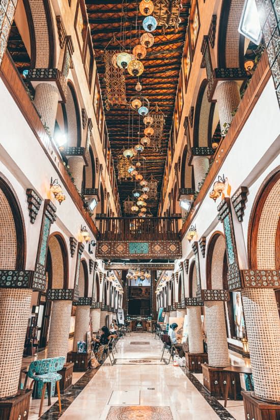 the inside of a large building with lots of lights hanging from it's ceiling