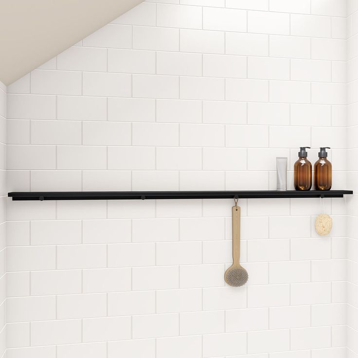 a bathroom with white tile and black shelf above the bathtub is seen in this image