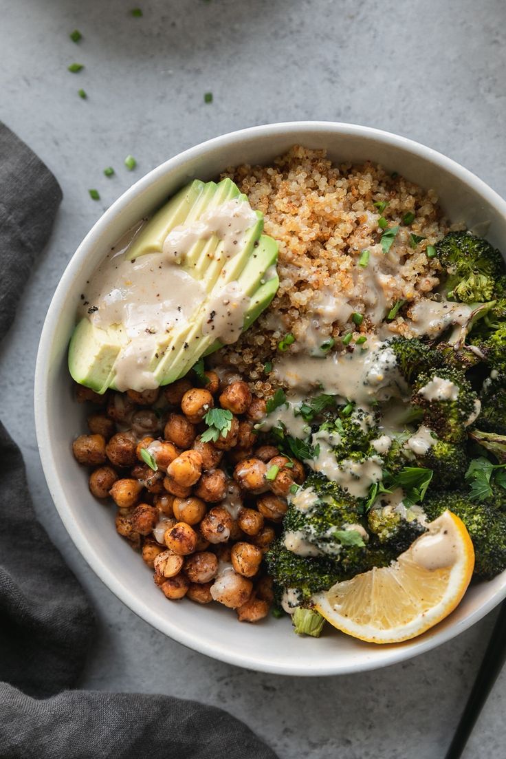 a white bowl filled with broccoli, chickpeas and other food items