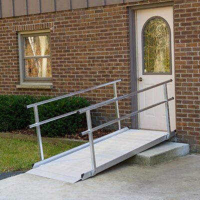 a metal hand rail next to a white door with a window on the side of a brick building