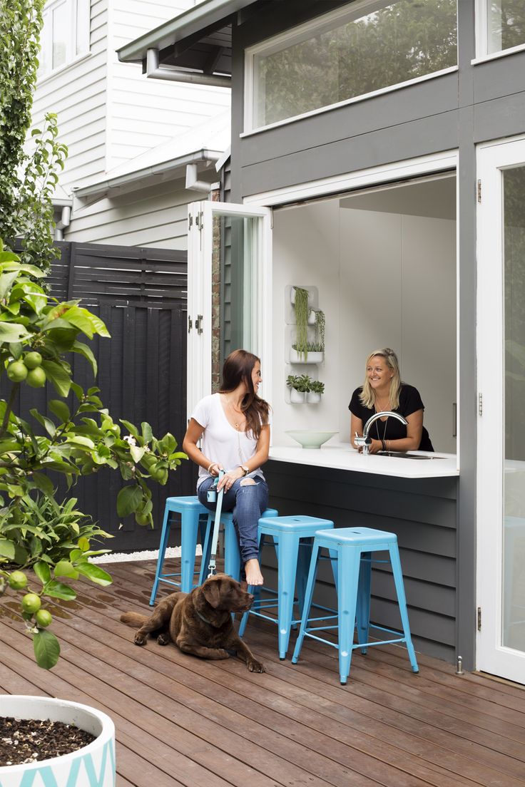 two women sitting on stools outside with a dog