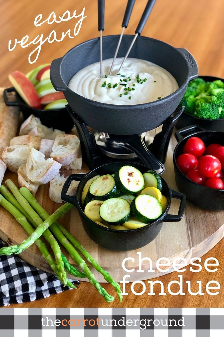 a cheese fondue is served with asparagus, cucumbers and tomatoes