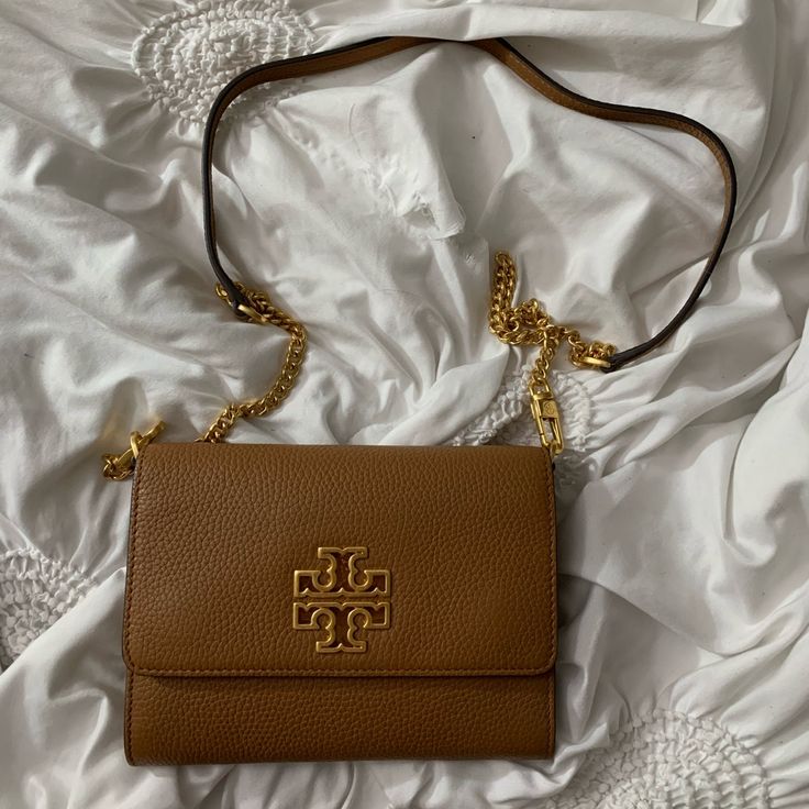 Brown With Gold Symbol/ Britten Chain Wallet Tory Burch Bag Aesthetic, Luxury Tan Bag With Chain Strap, Chic Gold Wallet On Chain With Branded Hardware, Designer Wallet On Chain With Gold-tone Hardware For Everyday, Designer Wallet On Chain For Everyday Use, Luxury Tan Rectangular Wallet On Chain, Everyday Wallet On Chain With Gold-tone Hardware, Rectangular, Luxury Rectangular Tan Wallet On Chain, Crossbody Wallet On Chain With Branded Hardware