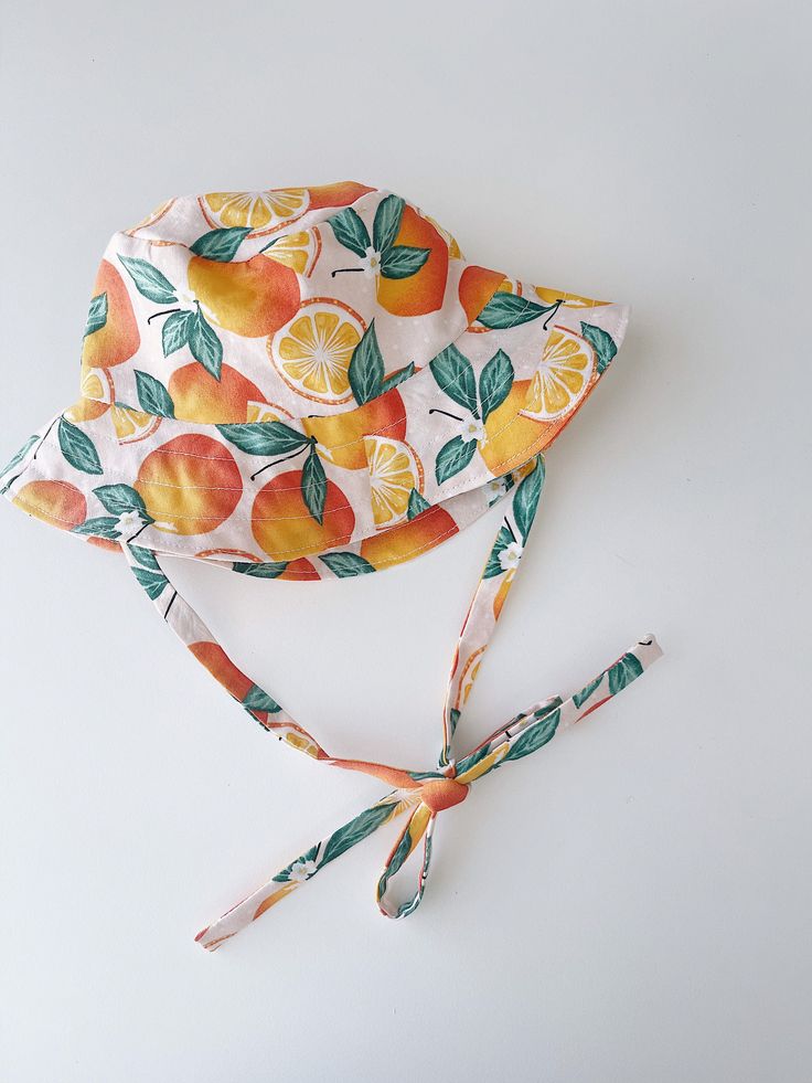 "Handmade brimmed orange print with soft pink background sun hat Breathable 100% cotton fabric Cotton lining | satin lining Measurements: Tie length for all - 16\" / 30-31 cm 0-3 months - 13\" / 33cm 3-6 months - 15\" / 38 cm 6-12 months - 17\" / 43cm 12-24 months - 18.5\" / 46-48 cm 2-4 years - 20\" / 50 cm 4-7 years - 20.5\" / 52 cm 7-12 years - 21.5\" / 54 cm Adult Small - 22\"/56 cm Adult Medium - 23\"/58 cm Adult Large - 24\"/60 cm Care instructions: Machine wash in cold water, gentle dry, Orange Summer Sun Hat For Vacation, Orange Summer Hat, Orange Brimmed Sun Hat For Vacation, Orange Brimmed Sun Hat For Summer, Orange Sun Hat For Summer, Orange Adjustable Summer Hat, Adjustable Orange Summer Hat, Cute Yellow Summer Sun Hat, Adjustable Orange Sun Hat For Summer