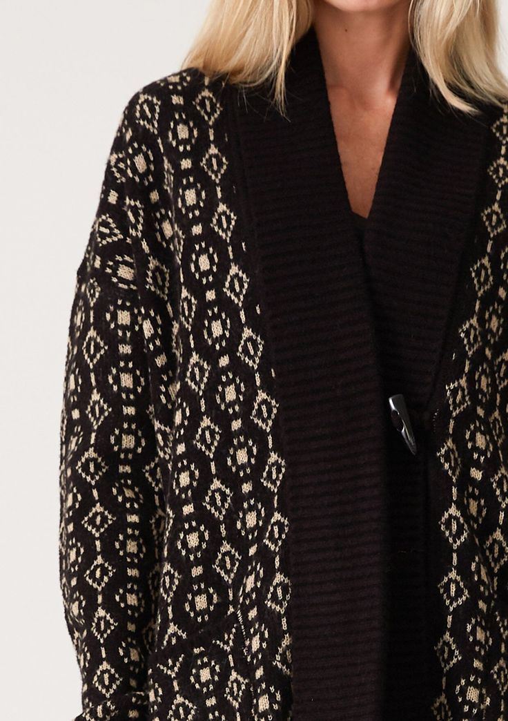 An ultra-warm mid-length cardigan in a black and taupe geo jacquard design. Geo jacquard Relaxed fit Long sleeve Drop shoulder Mid-length Shawl collar Toggle button closure Side pockets Contrast ribbed trim Bohemian cardigan An effortless slouchy cardigan designed in a cool geo jacquard pattern. Featuring a warm shawl collar, essential side pockets, and long sleeves with a relaxed dropped shoulder. The toggle closure secures at the front. Model is 5'9, wearing a size S/M. Style: I-50249K-SMG Beige Jacquard Knit Long Sleeve Outerwear, Brown Jacquard Knit Outerwear For Fall, Black Fair Isle Cardigan For Winter, Cozy Jacquard Knit Outerwear For Cold Weather, Black Fair Isle Winter Cardigan, Black Fair Isle Pattern Cardigan For Winter, Black Winter Outerwear With Fair Isle Pattern, Black Outerwear With Fair Isle Pattern For Winter, Black Jacquard Knit Outerwear For Fall