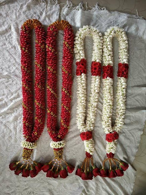 three red and white flower garlands with tassels attached to them on a bed