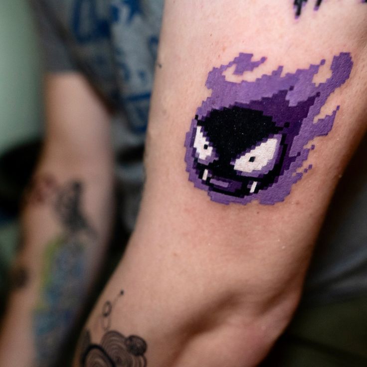 a close up of a person's arm with a pixel art tattoo on it