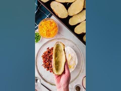 a person holding a hot dog bun over a plate of food