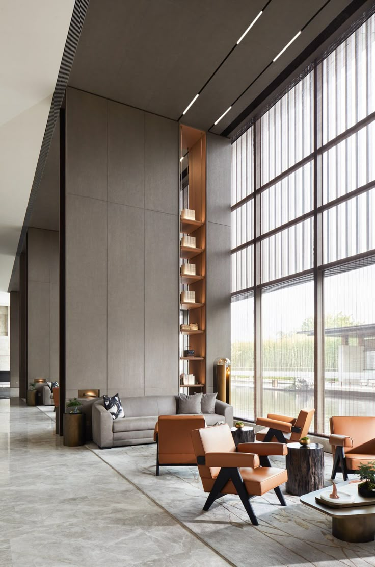 a living room filled with lots of furniture next to tall windows and floor to ceiling windows