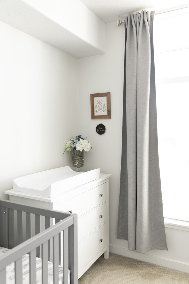 a baby's room with a crib, dresser and window