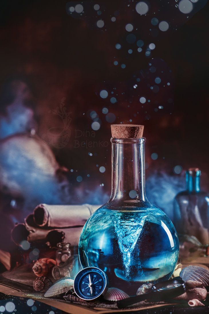 a glass bottle filled with blue liquid sitting on top of a table next to shells