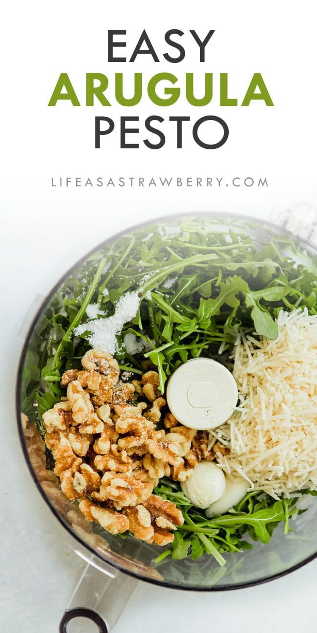 the ingredients for an easy arugula pesto salad in a food processor with text overlay