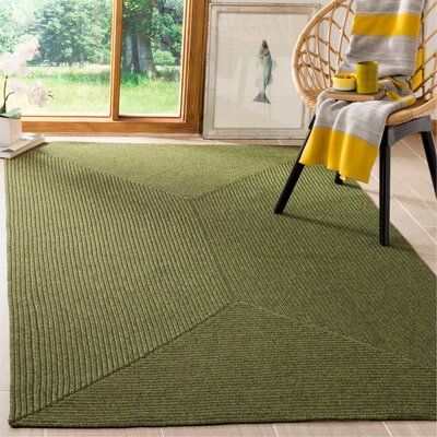 a green rug in a room with a wicker chair