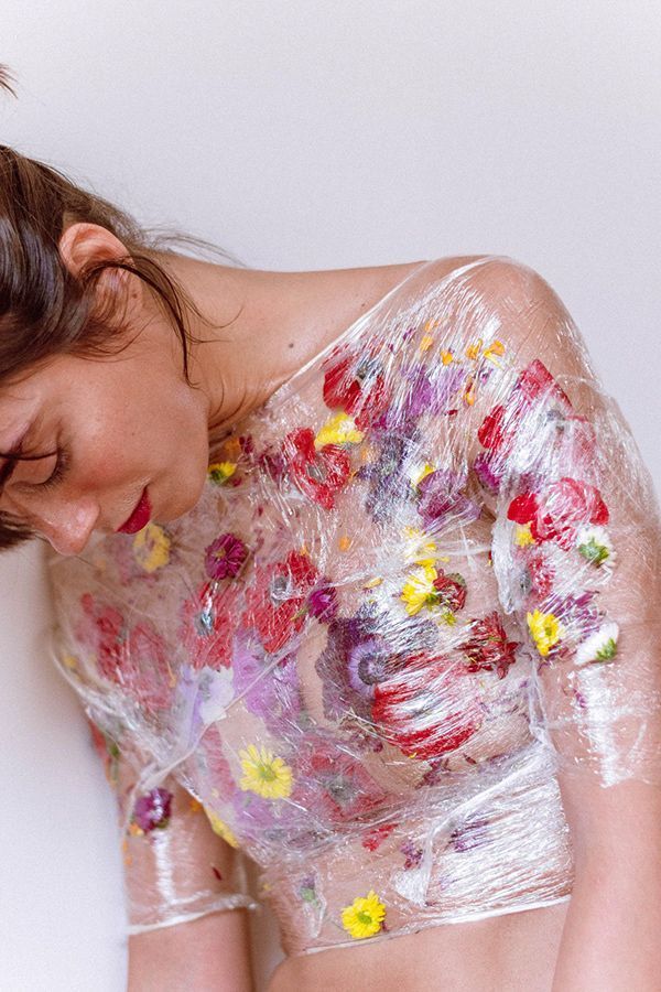 a woman covered in plastic with flowers on her body