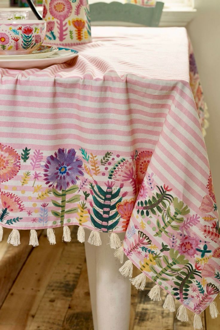 the table is covered with pink and white floral fabric, which has tassels on it