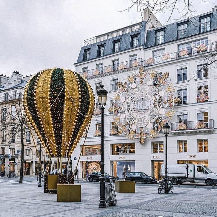 a large hot air balloon sitting in the middle of a street next to tall buildings