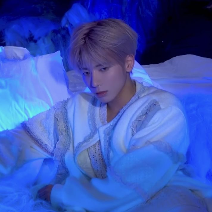 a person sitting on a bed in a room with blue lights and sheets around them