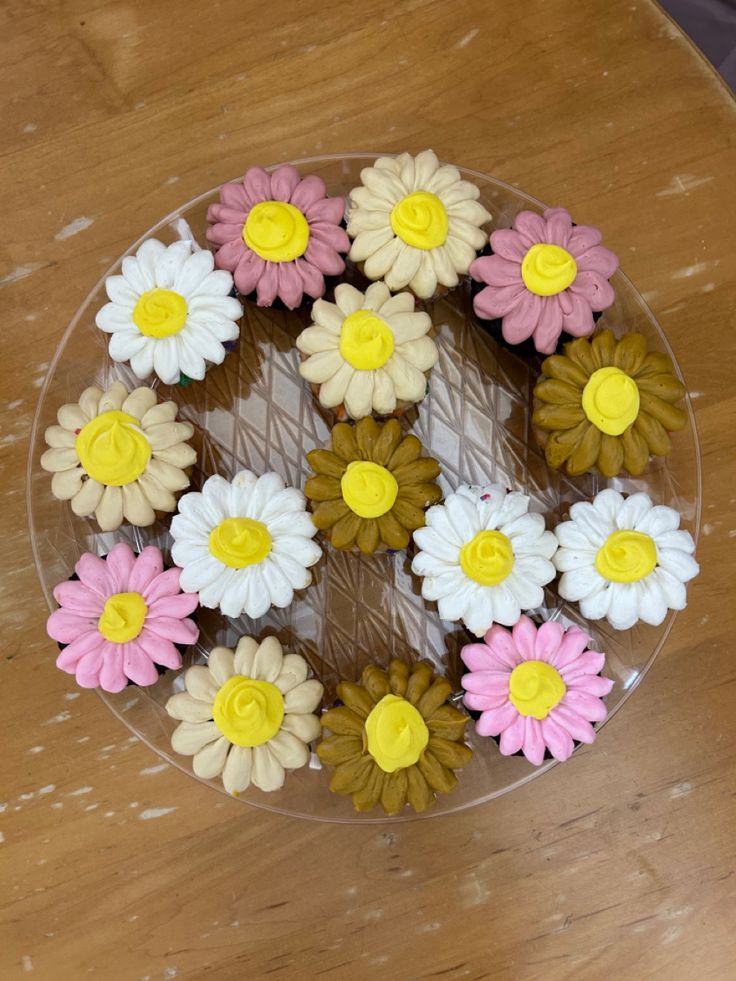 there is a glass plate with flowers on the wooden table and one has yellow, white, and pink ones