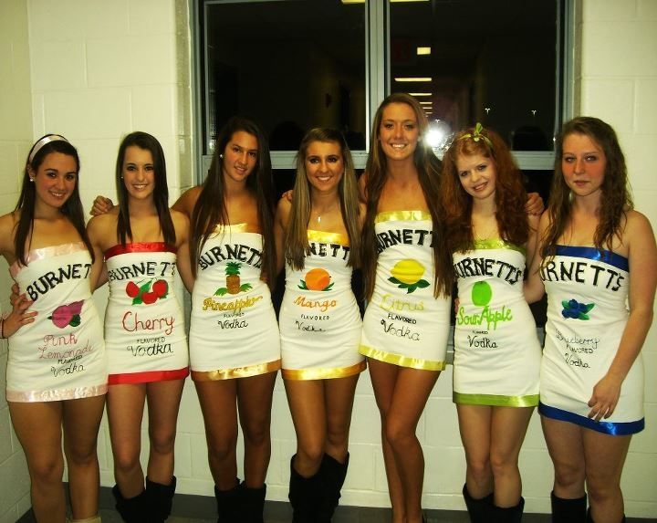 a group of young women standing next to each other in front of a window wearing costumes