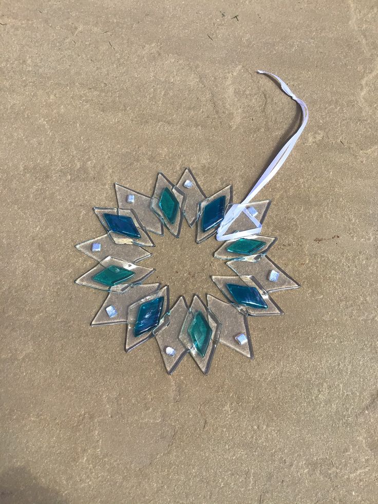 a snowflake ornament made out of glass and metal on the sand