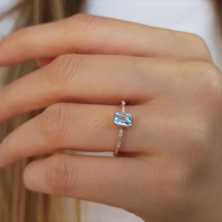 a woman's hand with a ring and an aqua blue topazte stone