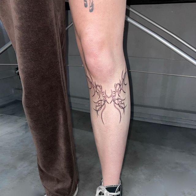 a person with tattoos on their legs standing next to another person's leg and foot