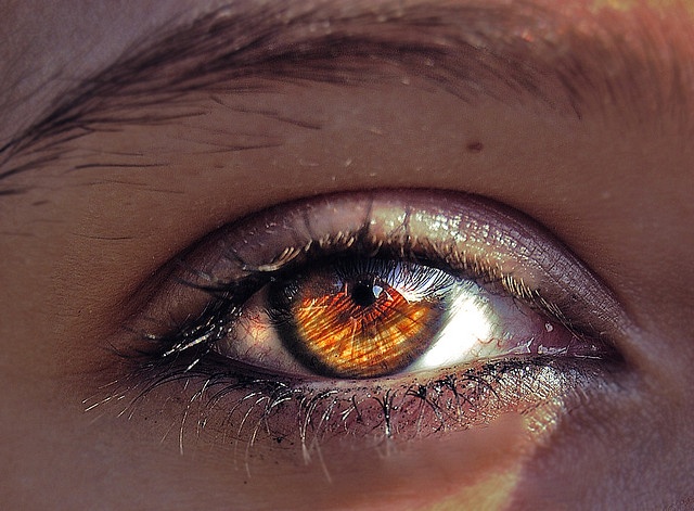 an orange eye is seen through the iris of someone's eye with long eyelashes