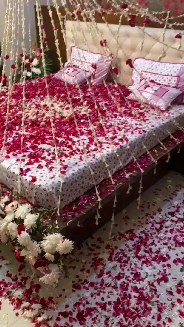 a bed with pink and white flowers on the bottom is surrounded by strings that are hanging from the ceiling