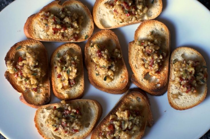 small pieces of bread with various toppings on a white plate