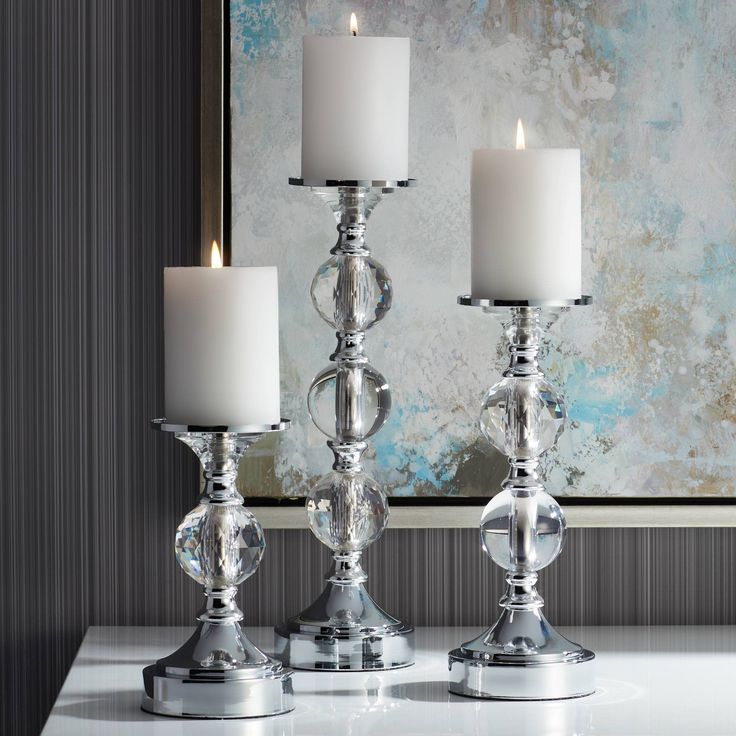 three silver candles are sitting on a table