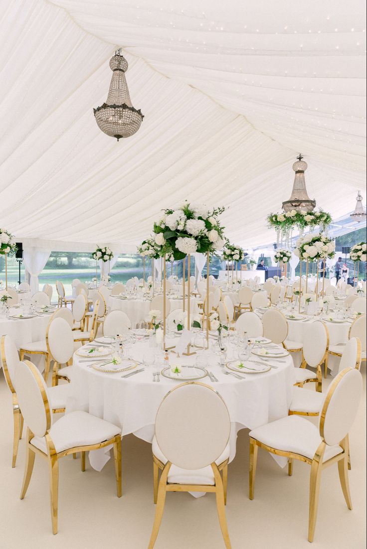 a large white tent with tables and chairs set up for a formal function or wedding reception