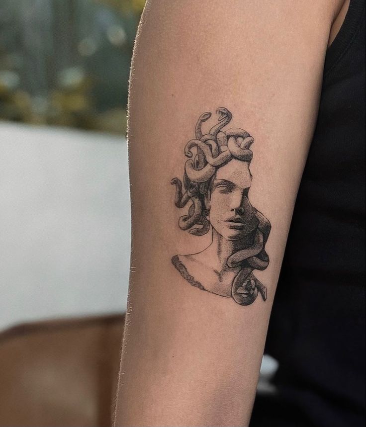 a woman's arm with a tattoo on it that has a snake crawling around her head