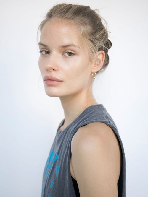 a woman with her hair in a bun is looking at the camera while wearing a tank top