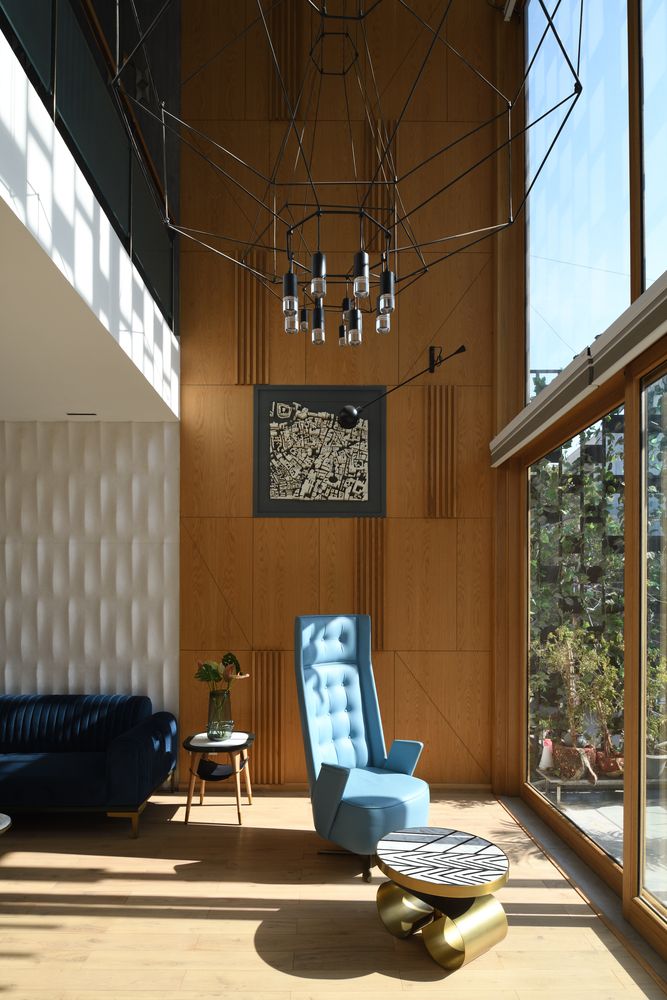 a living room filled with furniture next to a large glass window covered in light wood paneling