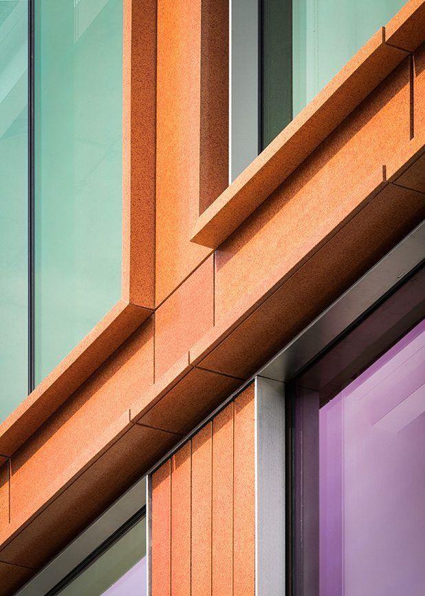 an orange building with purple windows and a clock on the side of it's face