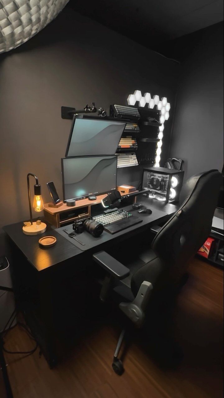 a computer desk with a monitor, keyboard and mouse on it in a dark room