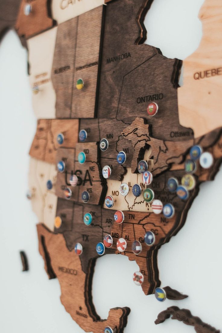 the wooden map of the united states is shown with pins and magnets on it