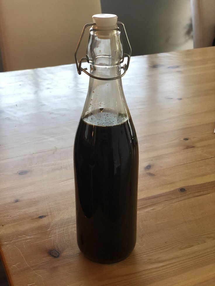 a glass bottle filled with liquid sitting on top of a wooden table