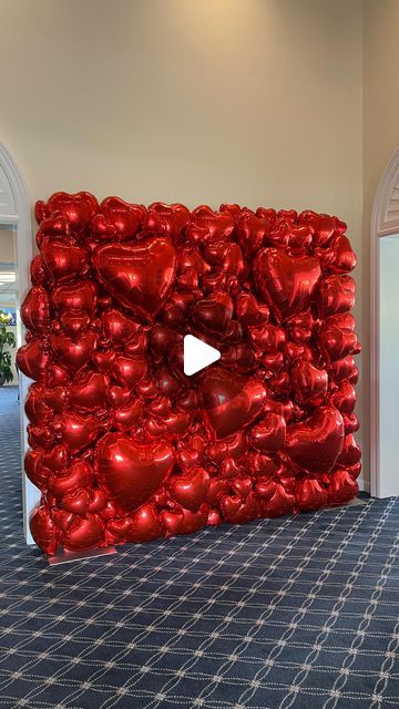 a giant red balloon wall in the middle of a room with an open door and video player on it